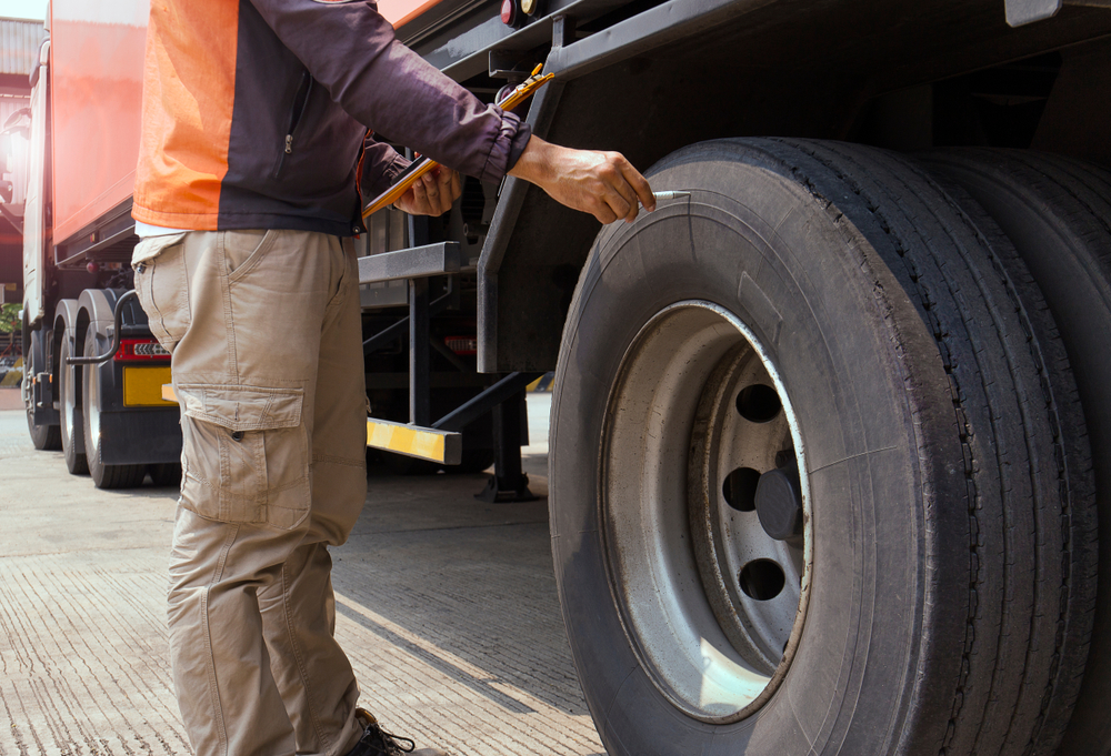 A man checking the tires of a truck.