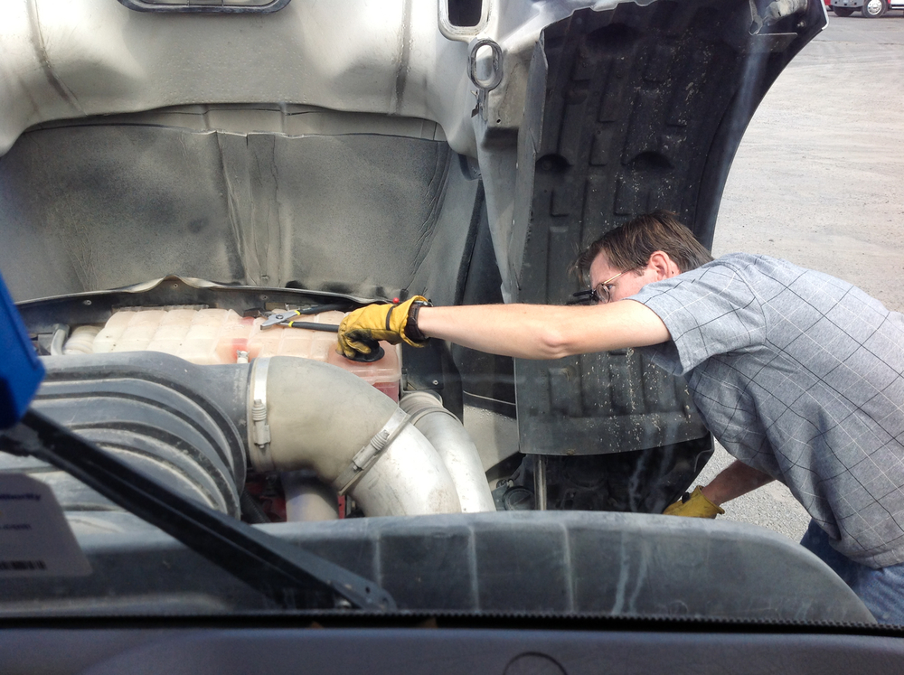 A man wearing gloves checking out the inside of a truck.